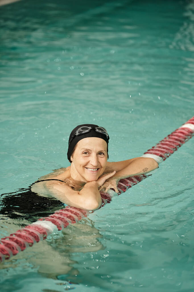 pozitív középkorú nő úszás medencében, mosoly, úszósapka és szemüveg, egészséges életmód, sport - Fotó, kép