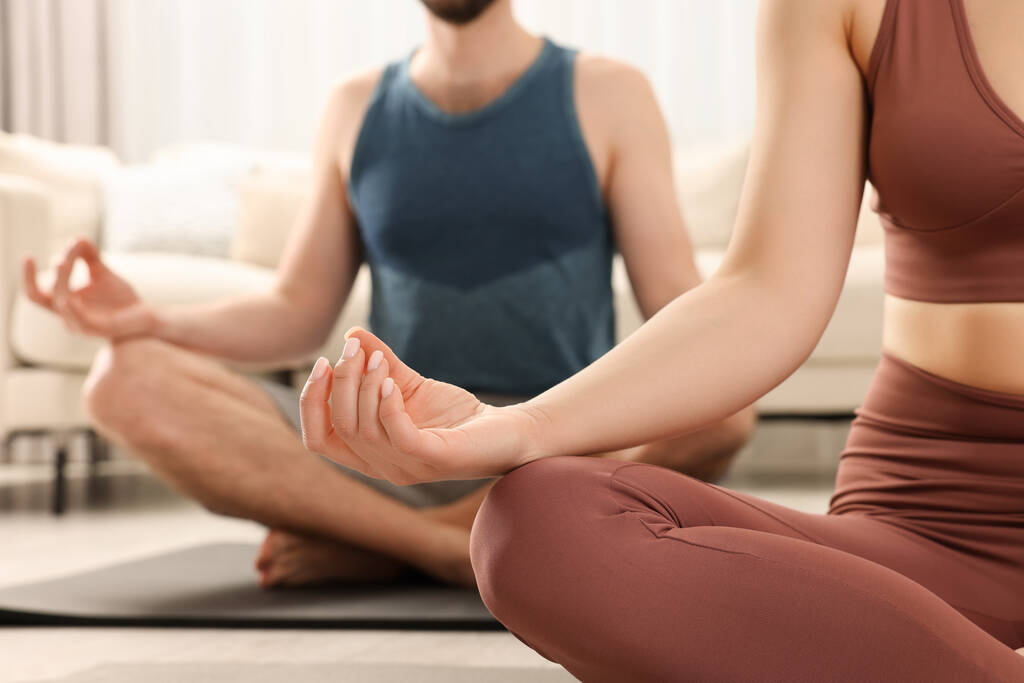 Egy pár sportruházatban együtt meditálnak otthon, közelről. Harmónia és zen - Fotó, kép