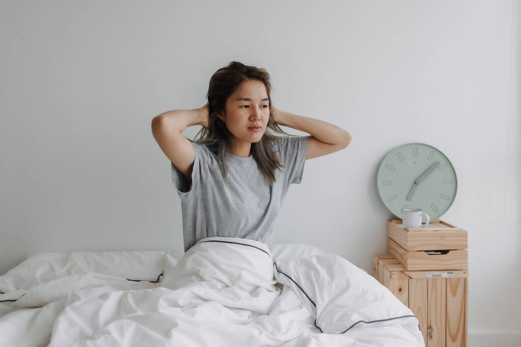 asiatico donna appena sveglia da il orologio a 7 am su il letto il mattina. - Foto, immagini