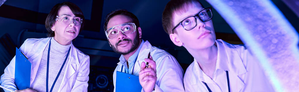 Μπάνερ, φουτουριστική εξερεύνηση: Διάφοροι επιστήμονες ερευνούν τη συσκευή στο επιστημονικό κέντρο Neon-Lit - Φωτογραφία, εικόνα