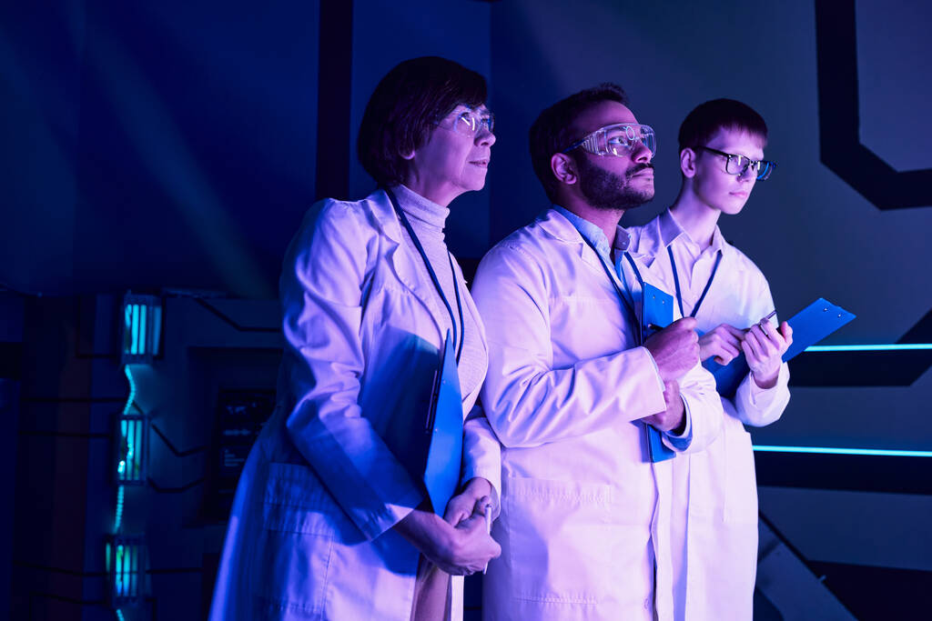 Futurisztikus megfigyelés: Három tudós vizsgálja meg az újonnan létrehozott eszközt a Neon-Lit Tudományos Központban - Fotó, kép