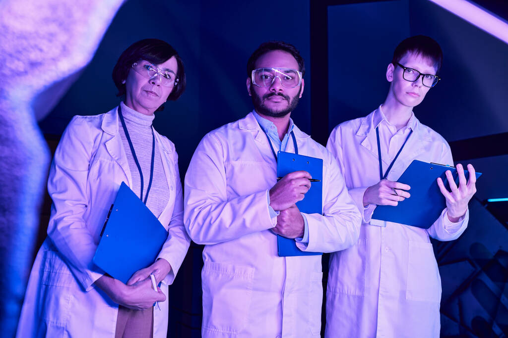 Φουτουριστική παρατήρηση: Τρεις επιστήμονες εξετάζουν τη συσκευή που δημιουργήθηκε πρόσφατα στο Neon-Lit Science Center - Φωτογραφία, εικόνα