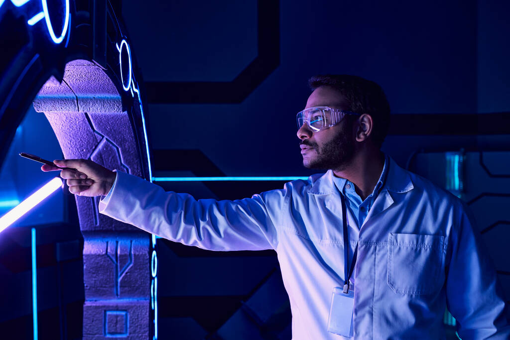 futuristický koncept, indický vědec v brýlích ukazující perem na nové zařízení ve vědeckém centru - Fotografie, Obrázek