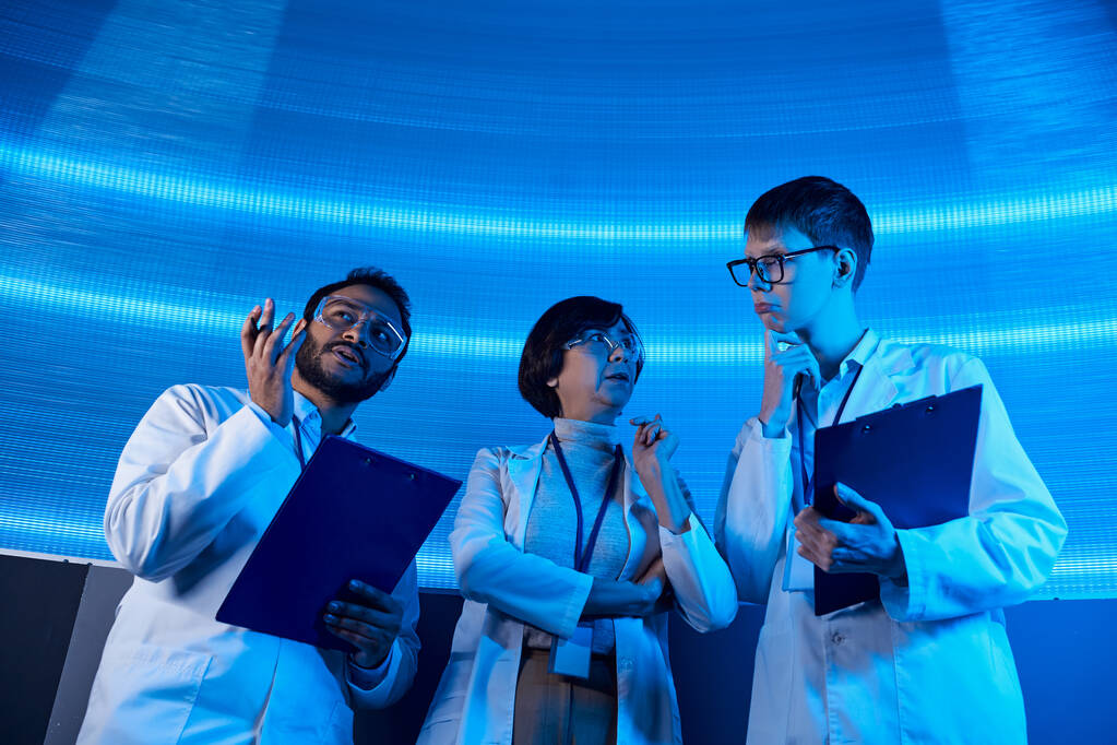 futuristic solutions, multiethnic scientists with clipboards talking in neon-lit discovery center - Photo, Image