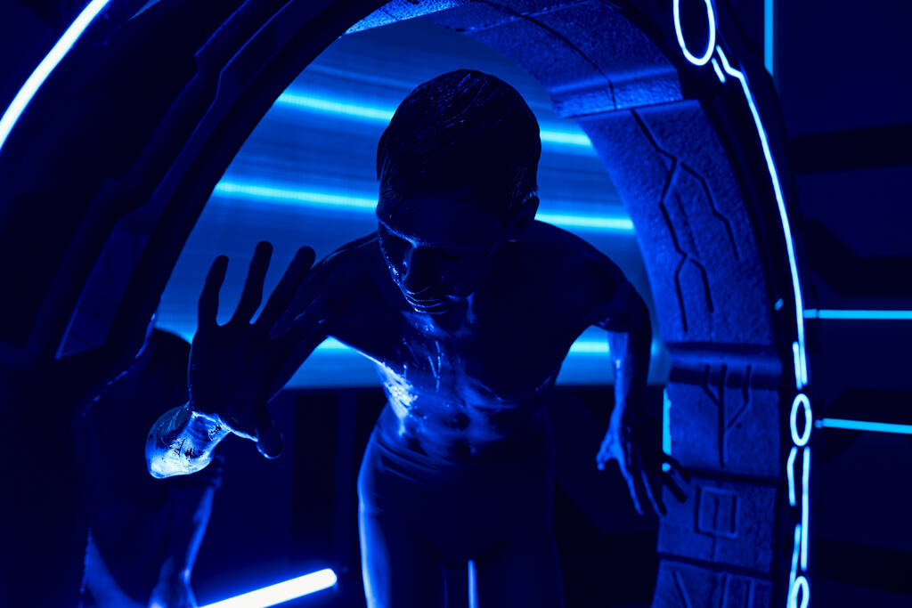 kosmický fenomén, mimozemský humanoid v blízkosti experimentálního vybavení v neonově osvětleném vědeckém centru - Fotografie, Obrázek