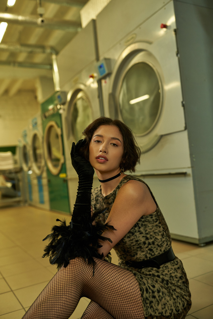 Asyalı şık bir kadın. Çamaşırhanede poz verirken kameraya bakıyor. - Fotoğraf, Görsel