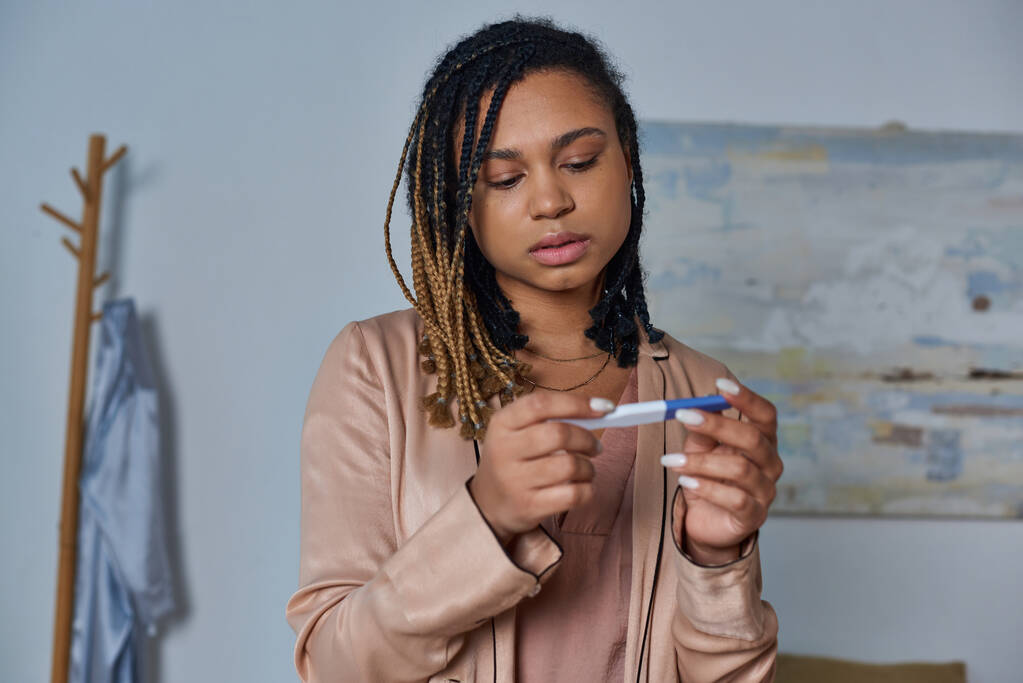 ιδέα έκτρωσης, Αφροαμερικανή γυναίκα που κοιτάζει το τεστ εγκυμοσύνης και παίρνει αποφάσεις, απροσδόκητα. - Φωτογραφία, εικόνα