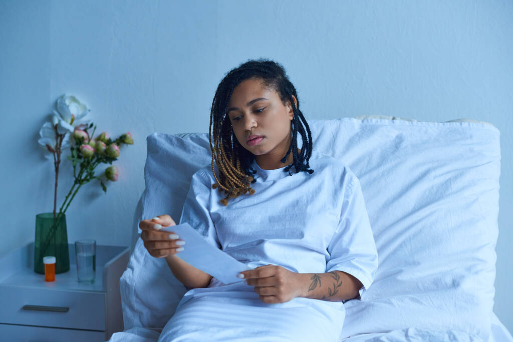prive-afdeling, verdrietig Afrikaans Amerikaanse vrouw in ziekenhuis toga kijken naar echografie, miskraam concept - Foto, afbeelding