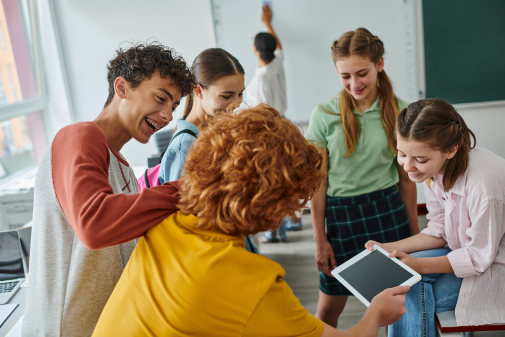 Alegre adolescente pupilos usando tableta digital con pantalla en blanco en el aula en la escuela - Foto, imagen