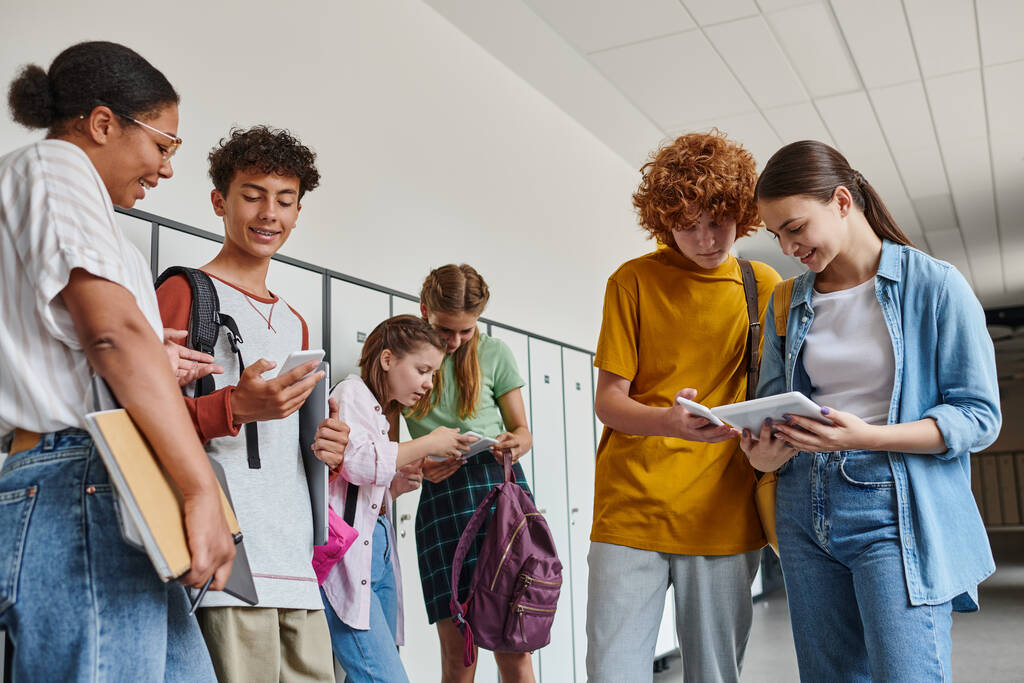 couloir de l'école, enseignant afro-américain près de l'adolescent, écoliers tenant des appareils, âge numérique - Photo, image