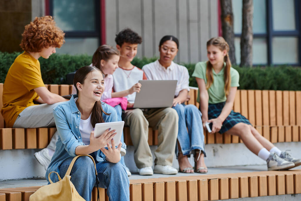 powrót do szkoły, nastolatka trzymająca cyfrowe tablety i śmiejąca się na zewnątrz, e-nauka, różnorodność, studenci - Zdjęcie, obraz