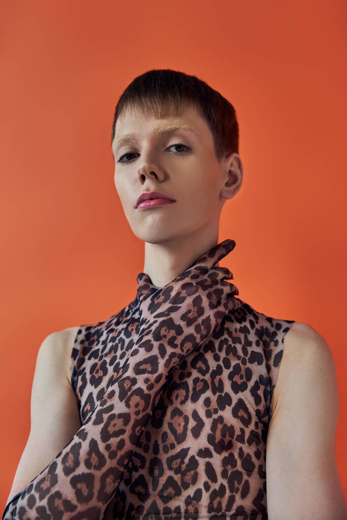 conceito de moda queer, jovem posando em pano de fundo laranja, impressão animal sem mangas, impressão de leopardo - Foto, Imagem