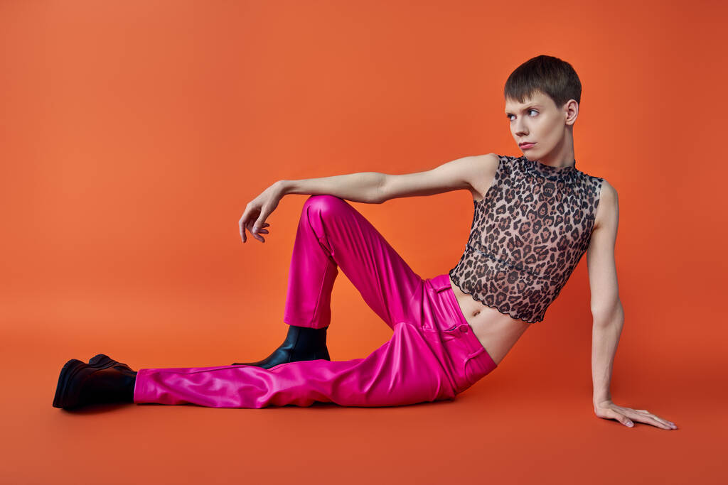 personne non binaire en léopard imprimé haut sans manches et pantalon rose sur fond orange, mode queer - Photo, image