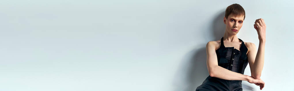 androgynní model v černém korzetu pózující na šedém pozadí, podivná móda, lgbtq, hranatý styl, banner - Fotografie, Obrázek
