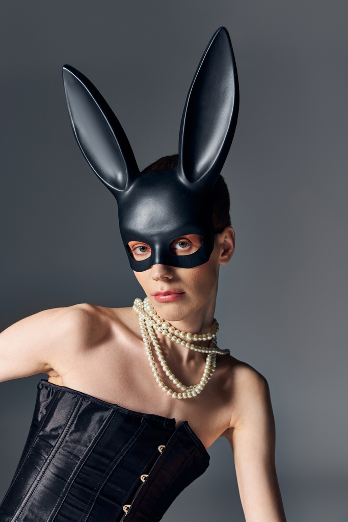 bold look, genderqueer person in corset posing in bdsm bunny mask on grey, moda queer, estilo - Foto, Imagem