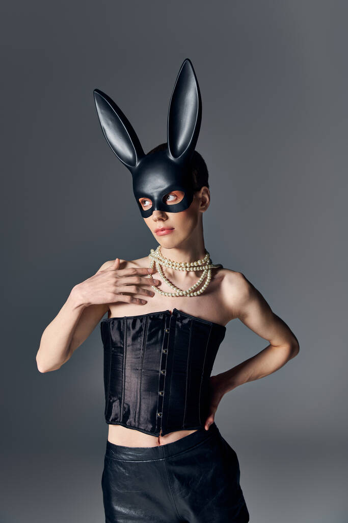 moda, płeć w gorsecie pozowanie w bdsm maska króliczka na szary, queer styl, ręka na biodrze - Zdjęcie, obraz