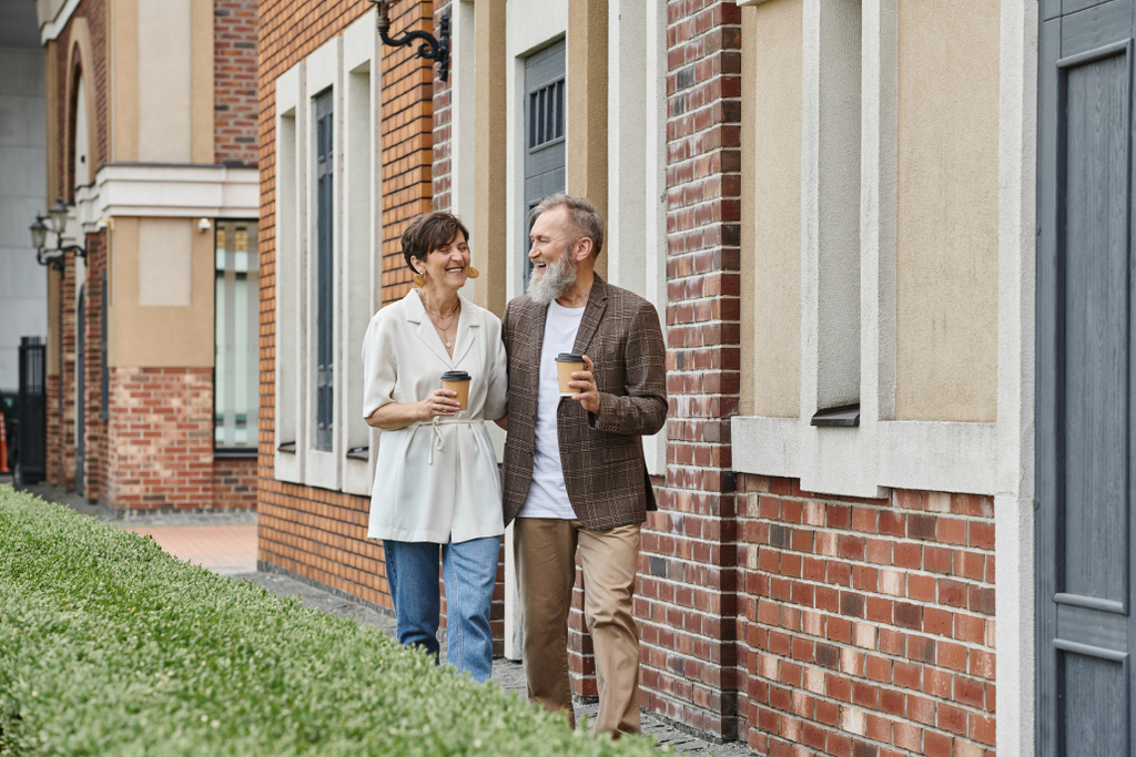 glückliches älteres Paar mit Kaffee to go, zu Fuß in der Nähe von Gebäuden, Mann und Frau, ältere Menschen, Romantik - Foto, Bild