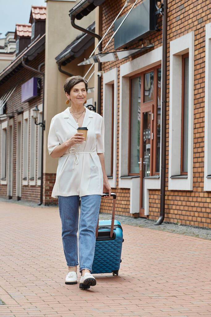 šťastný starší žena drží papírový pohár a procházky se zavazadly, káva jít, městský životní styl - Fotografie, Obrázek