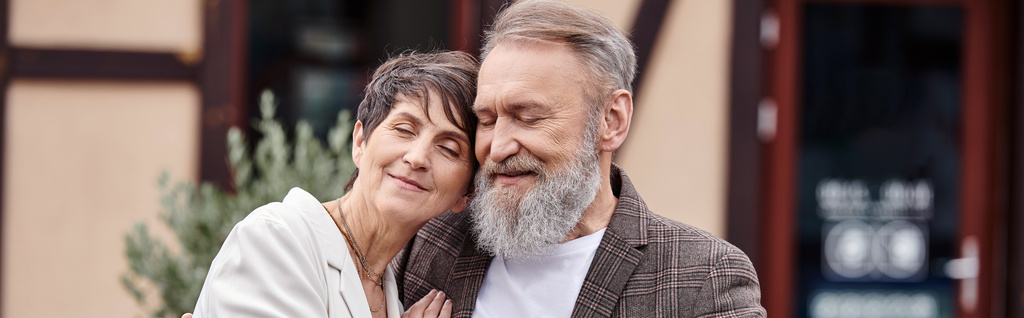 feliz hombre y mujer abrazos, pareja de ancianos con los ojos cerrados, romance, amor, personas mayores en la fecha, bandera - Foto, imagen
