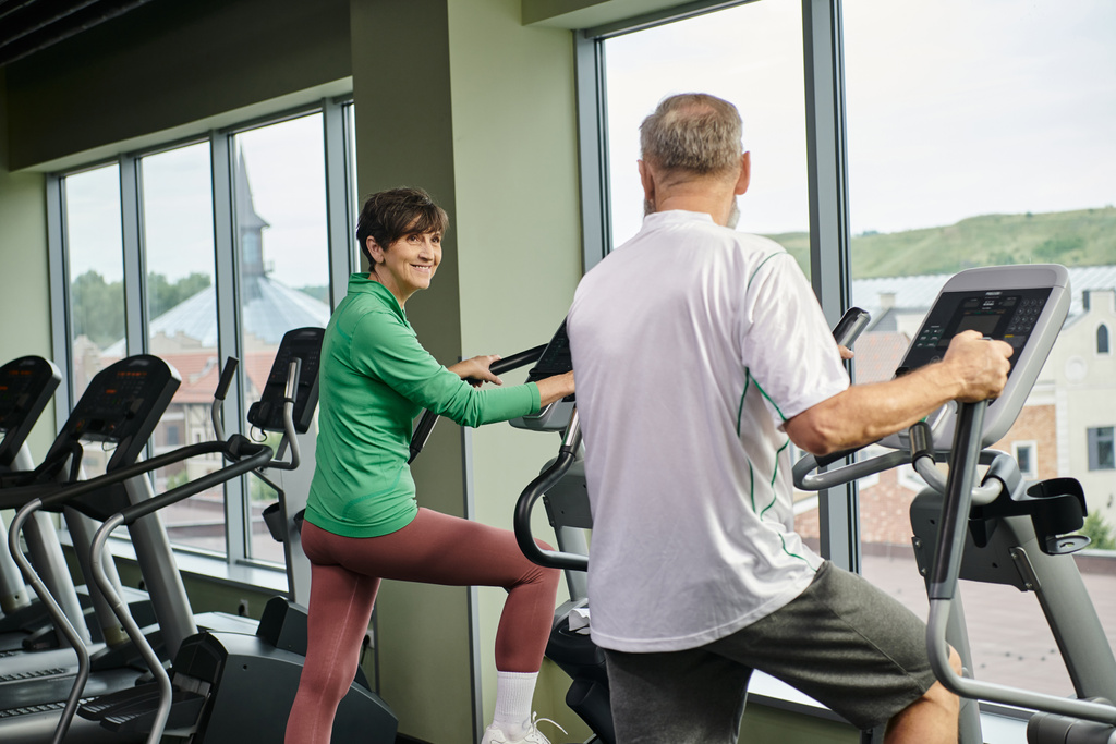 ενεργό ηλικιωμένους, ευτυχισμένη γυναίκα κοιτάζοντας ηλικιωμένους άνδρες στο γυμναστήριο, την άσκηση μαζί, ηλικιωμένοι ζευγάρι - Φωτογραφία, εικόνα