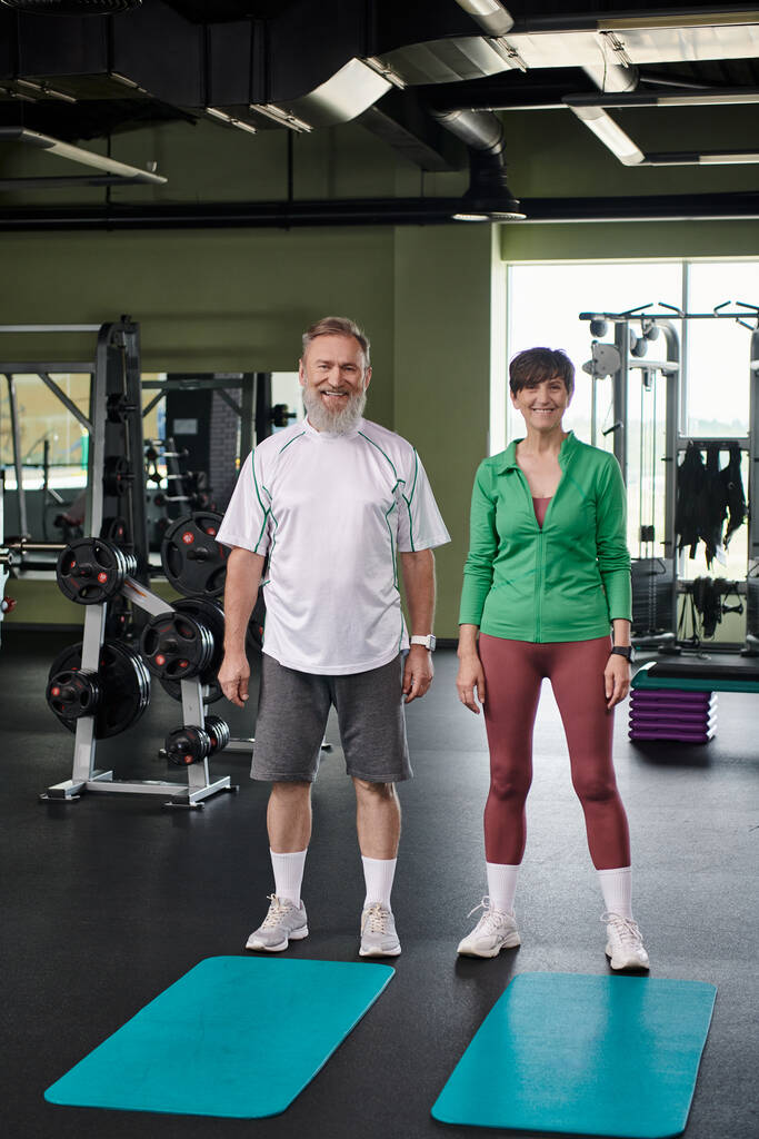šťastný starší pár stojící u fitness rohoží, dívající se na kameru, plná délka, aktivní senioři - Fotografie, Obrázek
