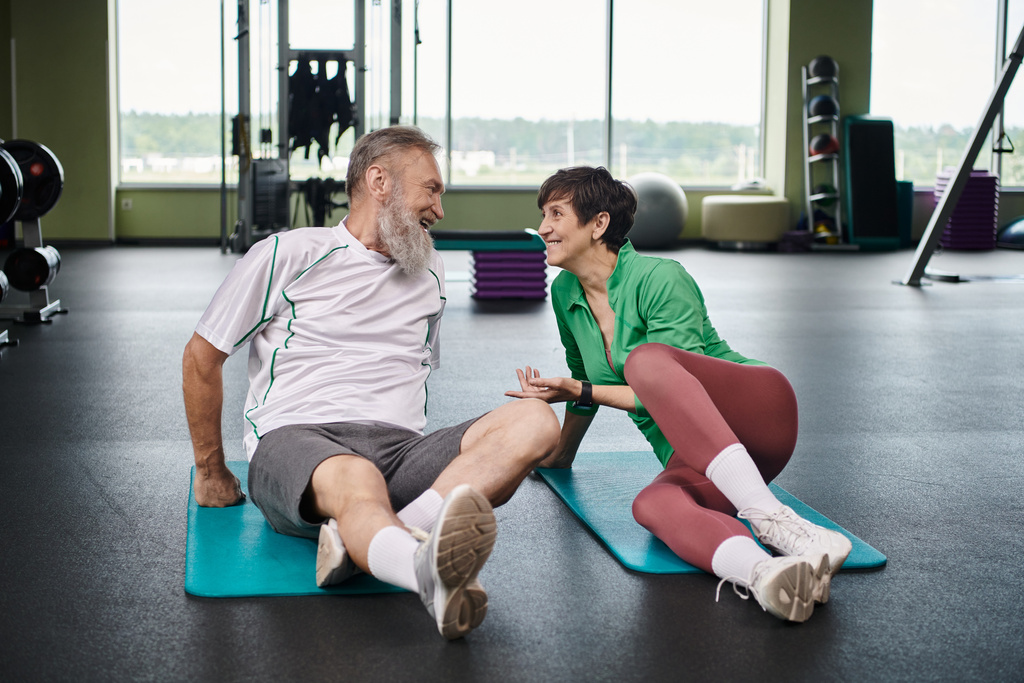 starší muž a žena dívají na sebe, aktivní senioři cvičení na fitness rohože v tělocvičně - Fotografie, Obrázek
