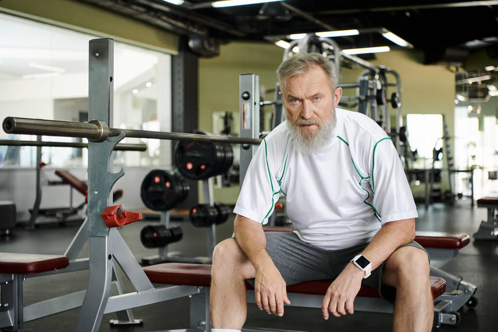 κουρασμένος ηλικιωμένος άνδρας με γενειάδα κοιτάζοντας κάμερα μετά την προπόνηση, γυμναστήριο, αθλητής - Φωτογραφία, εικόνα