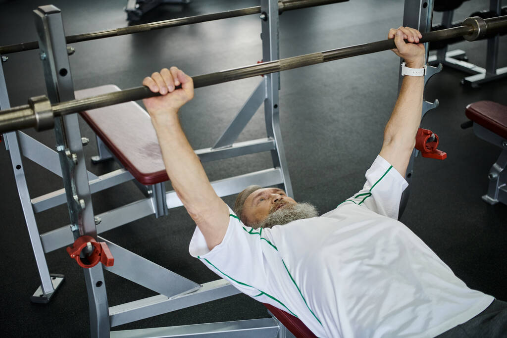 homme âgé fort avec barbe travailler avec haltère dans la salle de gym, senior actif, athlète, force - Photo, image