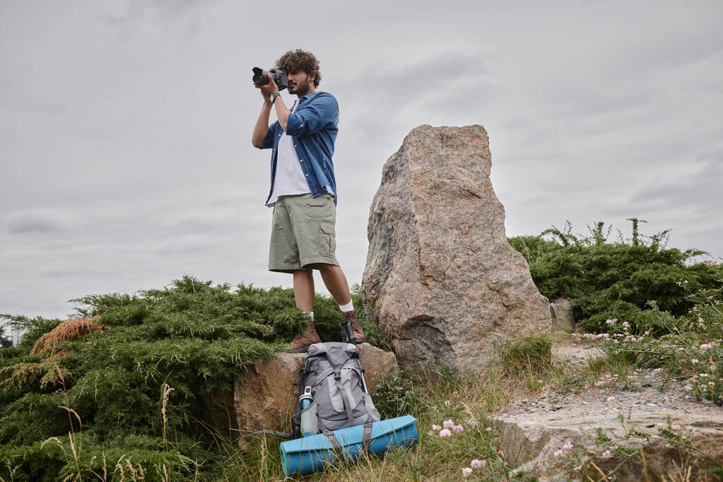 fotografia i koncepcja przyrody, indiański Backpacker biorąc strzał na aparat cyfrowy i stojąc na skale - Zdjęcie, obraz