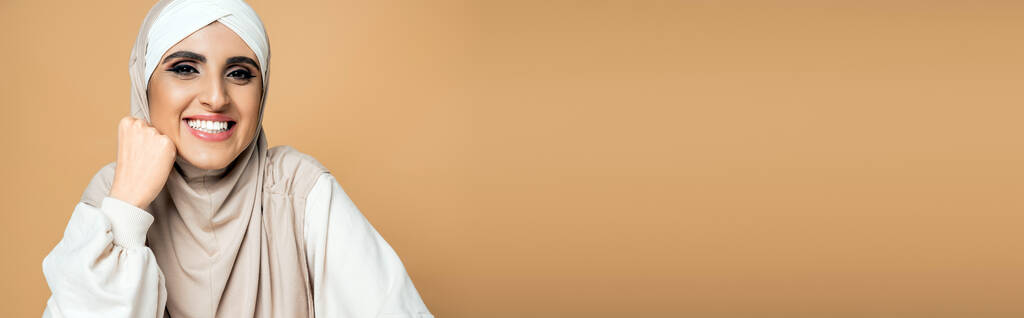 iloinen musliminainen valkoisessa paidassa ja hijabissa katselee kameraa beige, henkilökohtainen tyyli, banneri - Valokuva, kuva