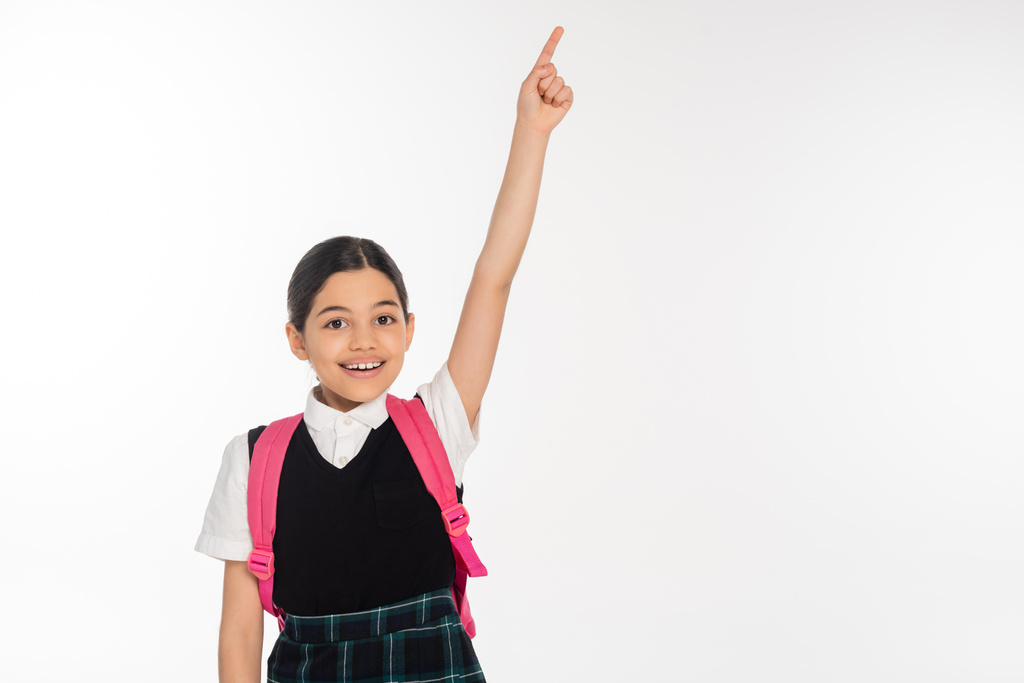 felice ragazza in uniforme scolastica mostrando qualcosa, indicando con il dito isolato su bianco, studente - Foto, immagini
