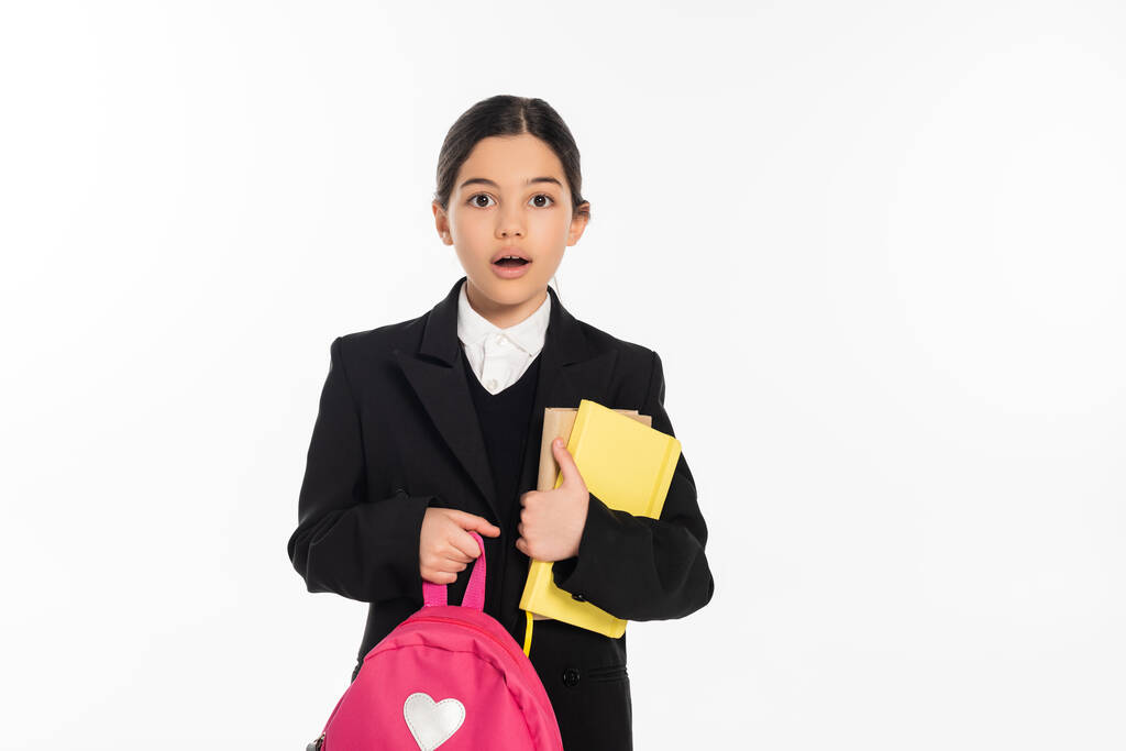 écolière choquée debout avec des cahiers et sac à dos sur blanc, concept de retour à l'école - Photo, image