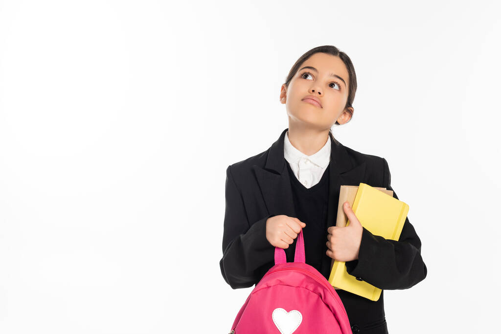 pensive schoolgirl standing with notebooks and backpack on white background, back to school, think - Photo, Image