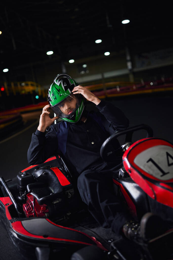 piloto decolando capacete e sentado em go kart após corrida em circuito interno, conceito de adrenalina - Foto, Imagem