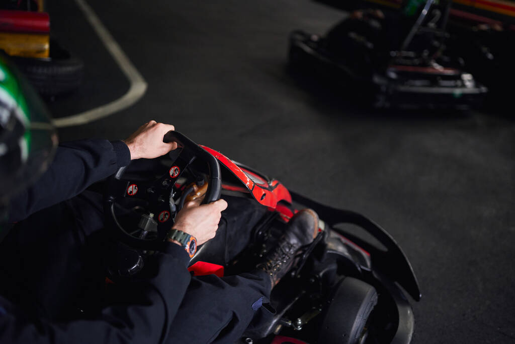 racer in helm en sportkleding rijden go kart op indoor circuit, stuurwiel, adrenaline concept - Foto, afbeelding