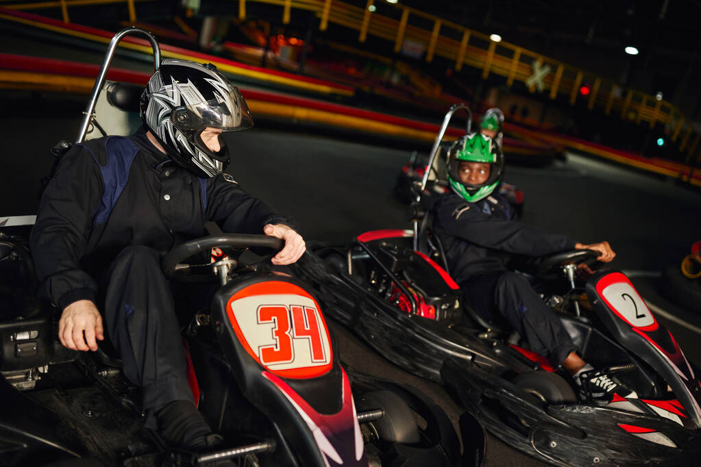 multiethnic competitors driving go kart on indoor circuit, speed racing and motorsport - Photo, Image