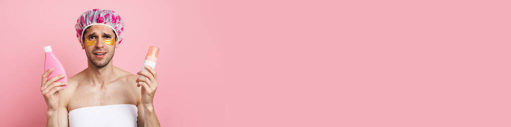 Молодой белый человек в шапочке для душа позировать с косметикой изолированы на розовом фоне - Фото, изображение