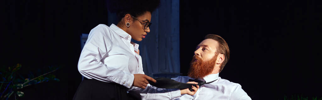 african american woman seducing bearded businessman and pulling his tie in night office, banner - Photo, Image