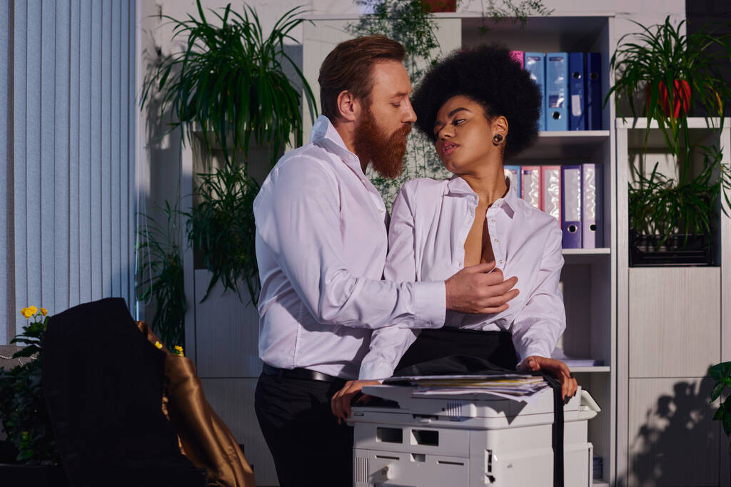 empresário barbudo seduzindo e despir jovem secretário afro-americano perto copiadora no escritório - Foto, Imagem