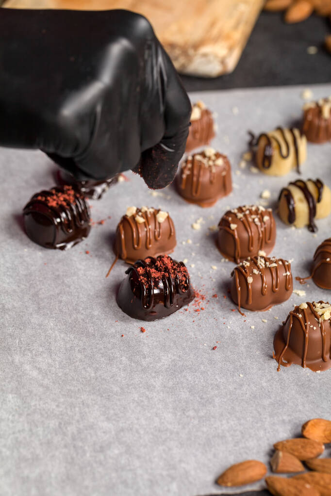 Sprinkle καραμέλα πάνω από αποξηραμένα σμέουρα. Ένα γλάσο σοκολάτας έχει εφαρμοστεί σε διάφορα σχήματα των σπιτικών καραμέλα - Φωτογραφία, εικόνα