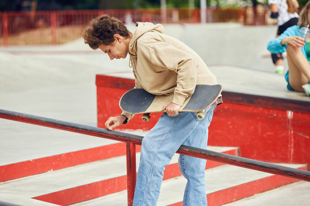 Adolescent en vêtements décontractés skateboard dans le skate park, en plein air, s'amuser avec des amis. Je fais des cascades. Concept de culture jeunesse, sport, dynamique, extrême, passe-temps, action et mouvement, amitié - Photo, image