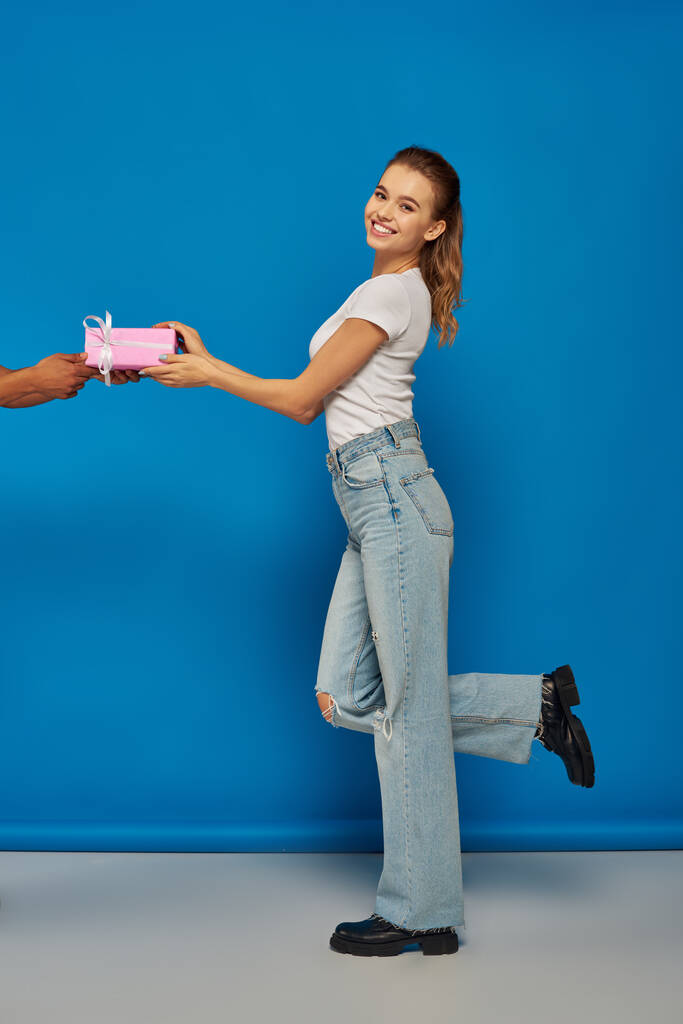 uomo afroamericano dare regalo alla donna eccitato su sfondo blu, occasioni festive - Foto, immagini