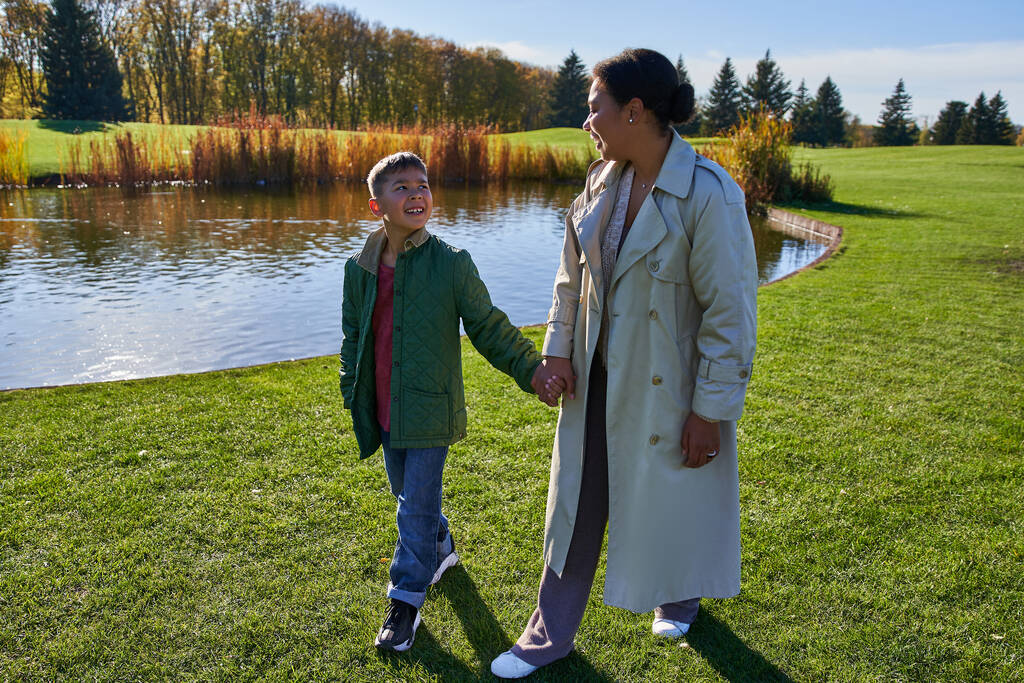 ボンディング,幸せな母親,息子は手を握り,公園の湖の近くを歩いています, アフリカ系アメリカ人の家族 - 写真・画像