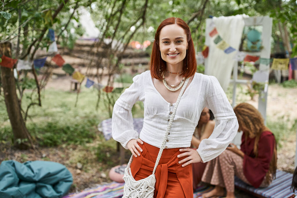 usmívající se červené vlasy žena v letním oblečení při pohledu na kameru venku v centru ústupu - Fotografie, Obrázek