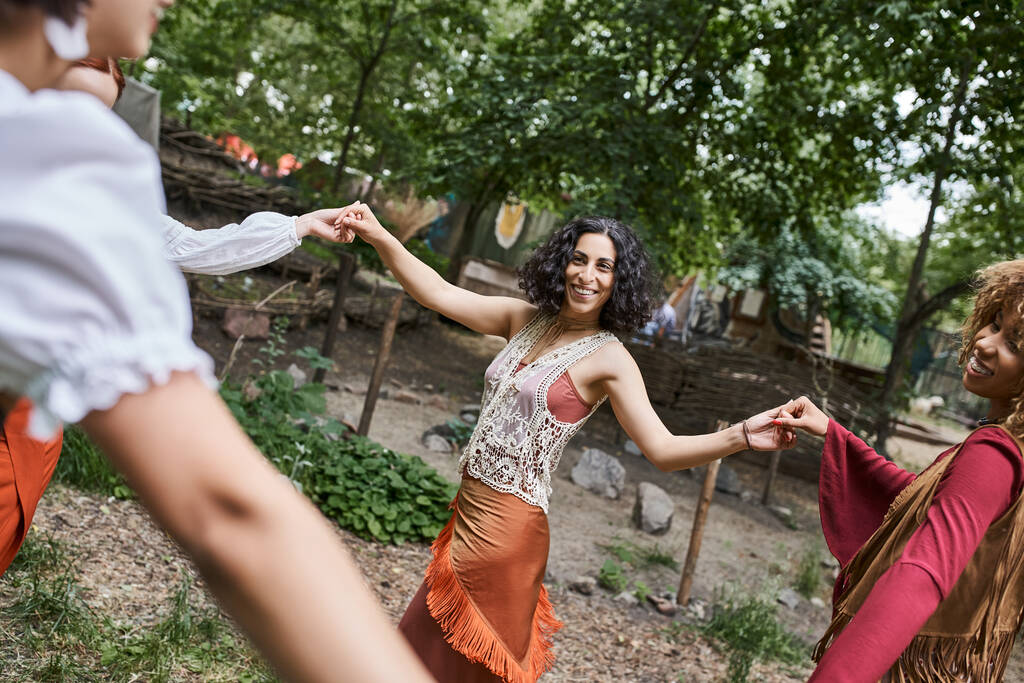 positive multiethnische Freundinnen Händchenhalten und Tanzen auf der Wiese im Retreat Center - Foto, Bild