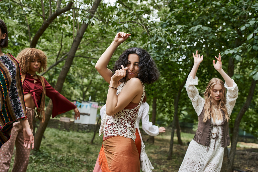joyful multiracial žena v boho oblečení dívá na kameru a tanec v centru ústupu - Fotografie, Obrázek