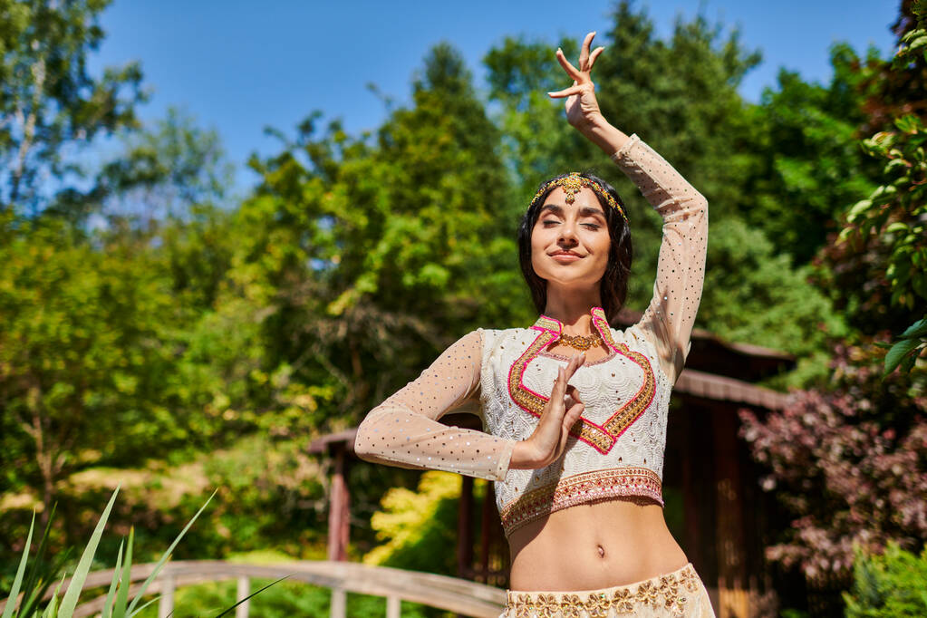 Sommerglück, junge Indianerin in ethnischer Kleidung tanzt mit geschlossenen Augen an sonnigem Tag im Park - Foto, Bild