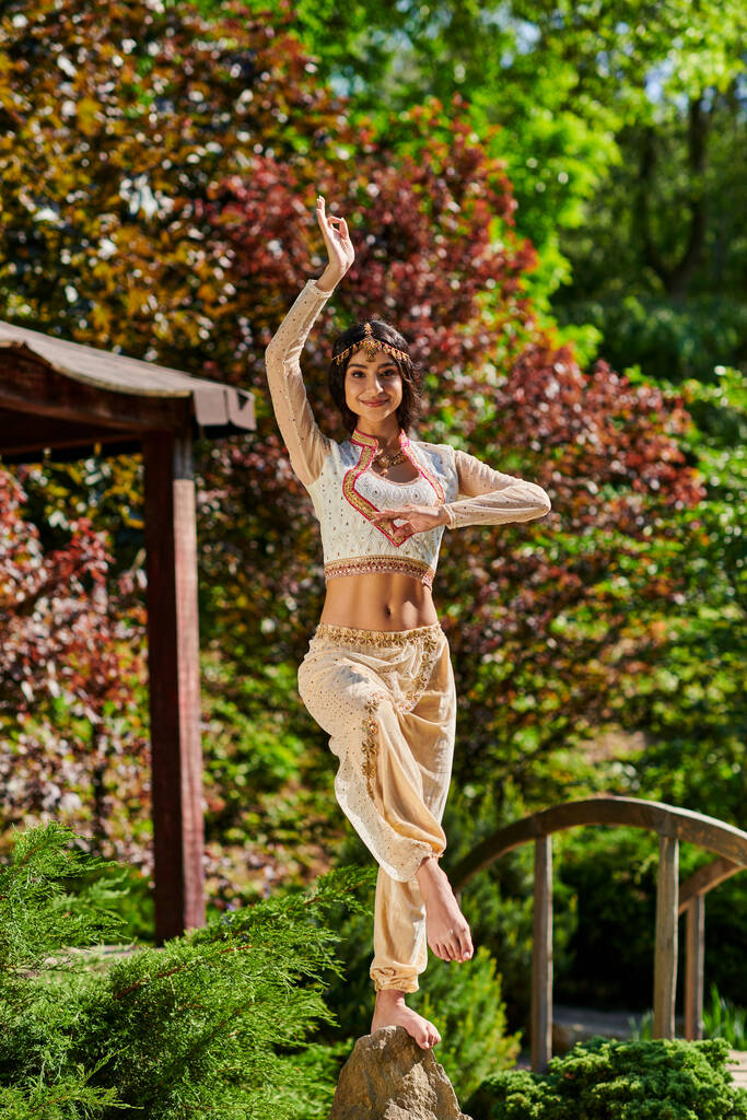 Esmer Hintli kadın otantik tarzda giyinmiş güneşli yaz gününde parkta dans ediyor. - Fotoğraf, Görsel