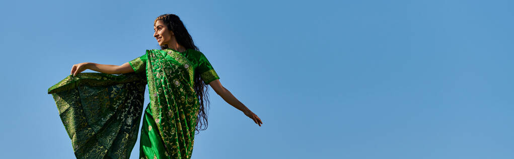loisirs d'été, femme indienne en sari souriant et regardant loin sous le ciel bleu sans nuages, bannière - Photo, image