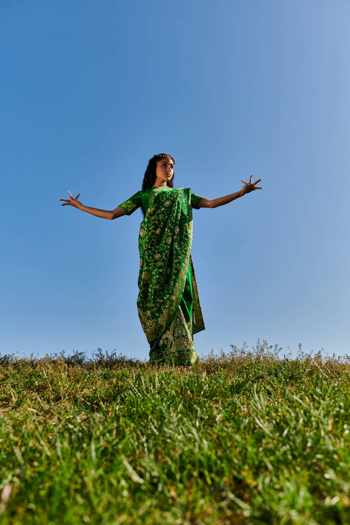 традиционная мода, молодая индийская женщина в сари с протянутыми руками под голубым летним небом - Фото, изображение